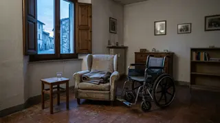 Contributo ai caregiver: poltrona vuota e carrozzina in un soggiorno italiano all'alba