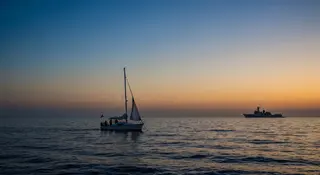 Rimpatrio attivisti Flotilla, barca umanitaria nel Mediterraneo al tramonto vista da silhouette navale