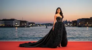 Red carpet Venezia 82, abito couture nero con piume di Margiela in posa sotto i flash della Mostra del Cinema