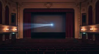 Nastassja Kinski contro Wenders: sala cinematografica vuota con proiettore acceso e cono di luce sul telone