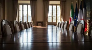 Tavolo permanente moda: sala riunioni istituzionale con bandiere di Italia e Francia e tessuti di alta sartoria