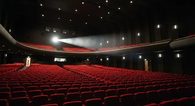 Odissea al box office: sala cinematografica gremita di poltrone rosse illuminate dal proiettore