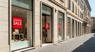 Saldi estivi 2026 in una via commerciale italiana con vetrine e cartelli sconto