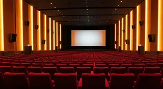 Sala cinematografica italiana vuota con poltrone rosse, simbolo del box office estate 2026