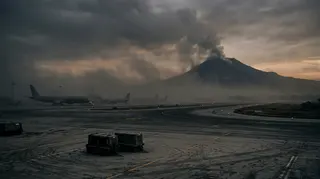 Voli limitati a Catania: pista dell aeroporto coperta di cenere vulcanica con l Etna in eruzione sullo sfondo