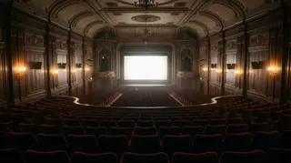 Sala cinematografica storica vuota con schermo acceso, la cornice del caso Dau a Venezia 83