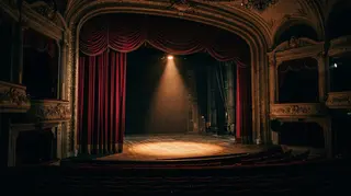 Palcoscenico teatrale vuoto illuminato da un occhio di bue, immagine simbolica per l'addio a Tim Curry