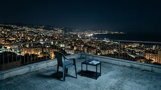 Naza Venezia 83: terrazza deserta di notte sopra una citta costiera illuminata, l'ambientazione delle testimonianze del documentario