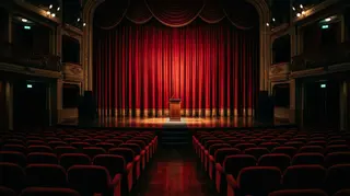 Woman Unknown Leone d'oro a Venezia 83: il palco vuoto della premiazione con sipario rosso e leggio illuminato