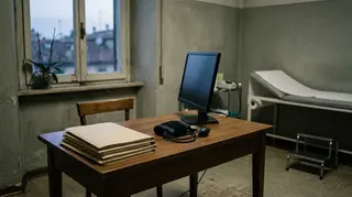 Dati sanitari anonimi: lo studio deserto di un medico di famiglia con cartelle chiuse sulla scrivania e monitor spento