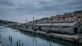 Lo stabilimento ex Ilva Cornigliano affacciato sulle banchine del porto di Genova al tramonto, capannoni delle lavorazioni a freddo deserti